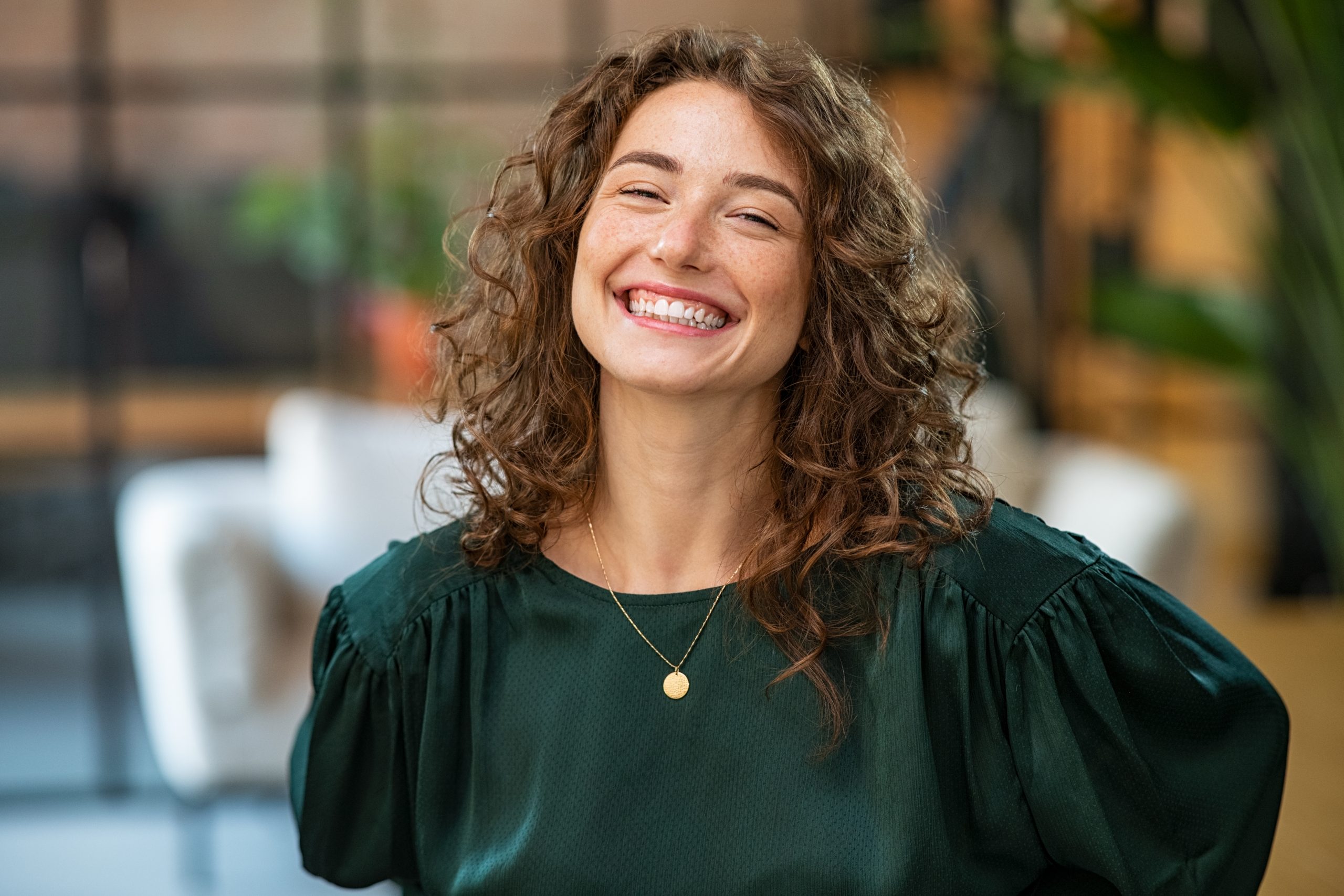 Smiling woman with curly hair in a green blouse