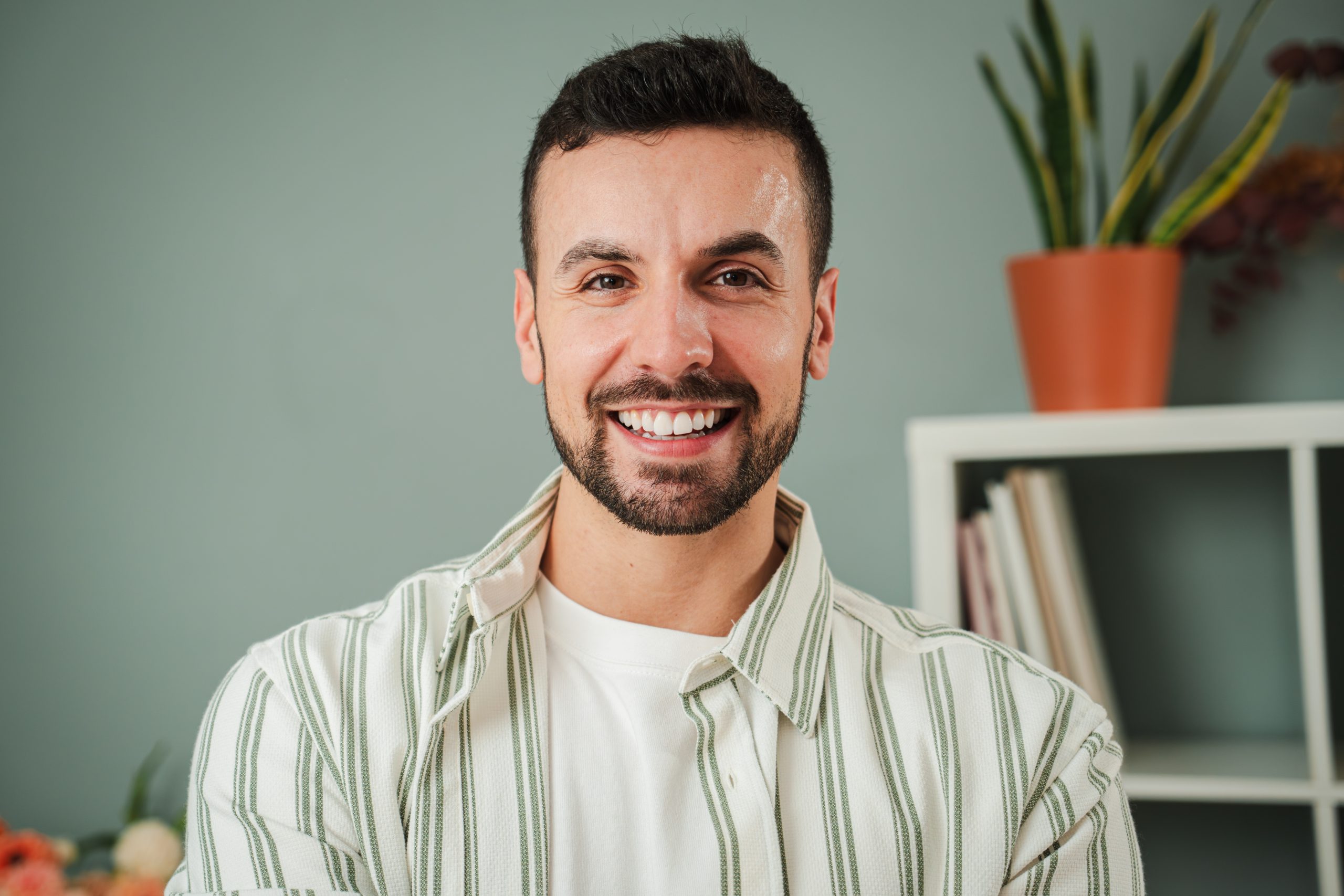 Smiling man with a beard in a striped shirt at home
