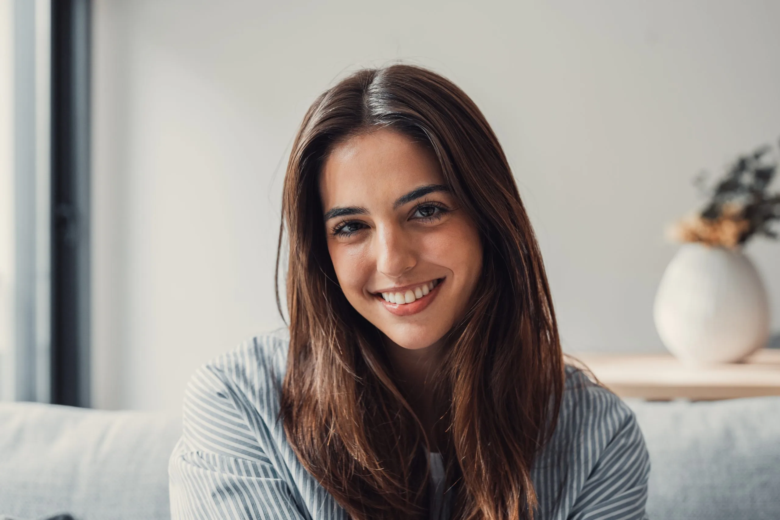 Smiling woman with long dark hair sitting at home