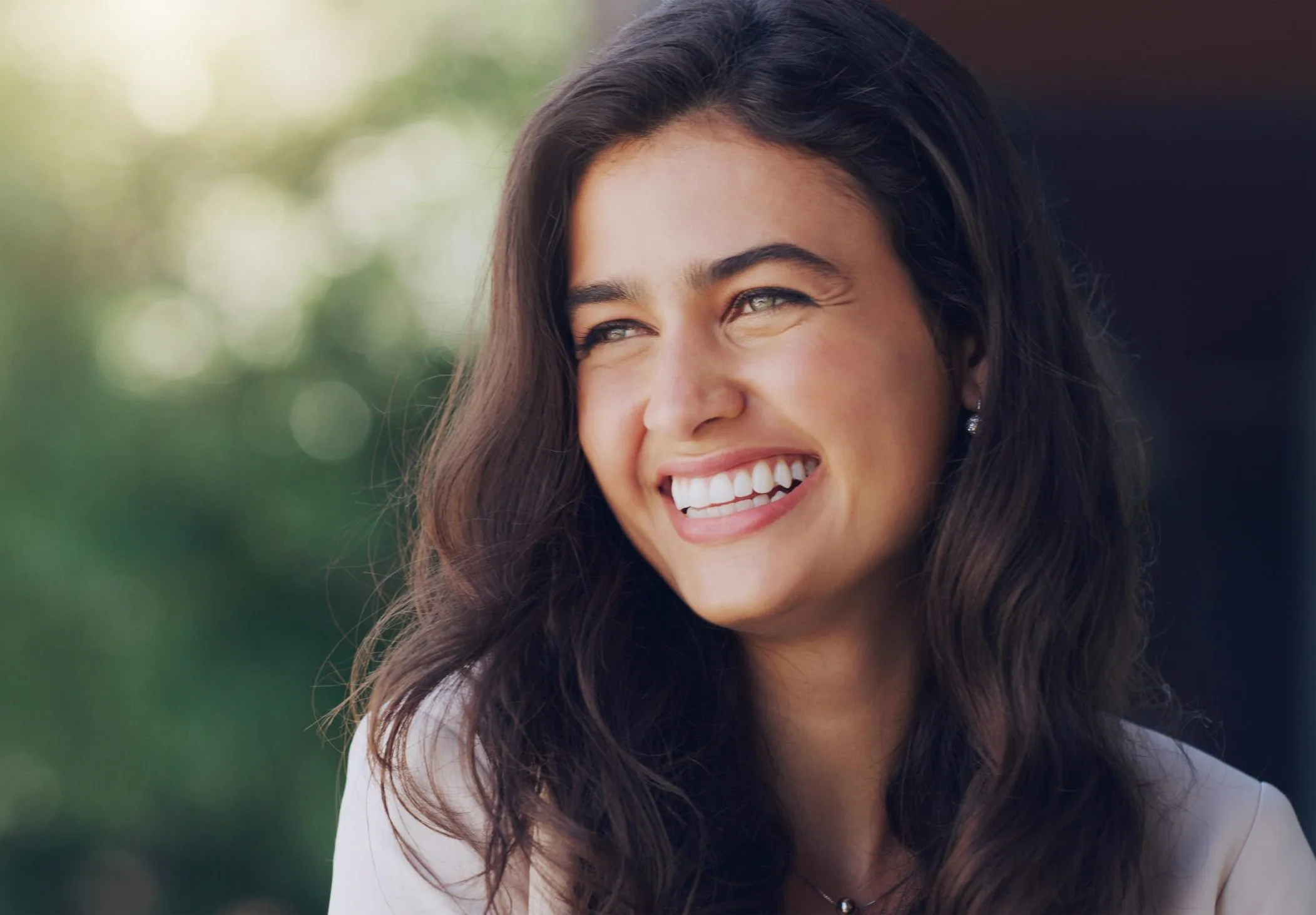 Smiling woman outdoors among green trees