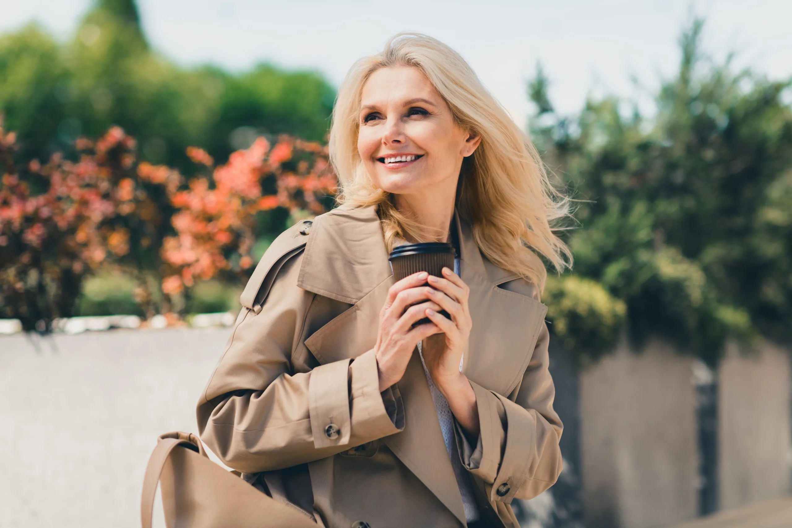 Smiling woman with a coffee cup walking outdoors