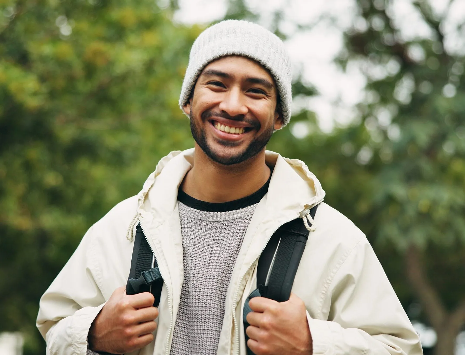 Smiling man in a beanie and jacket walking outdoors